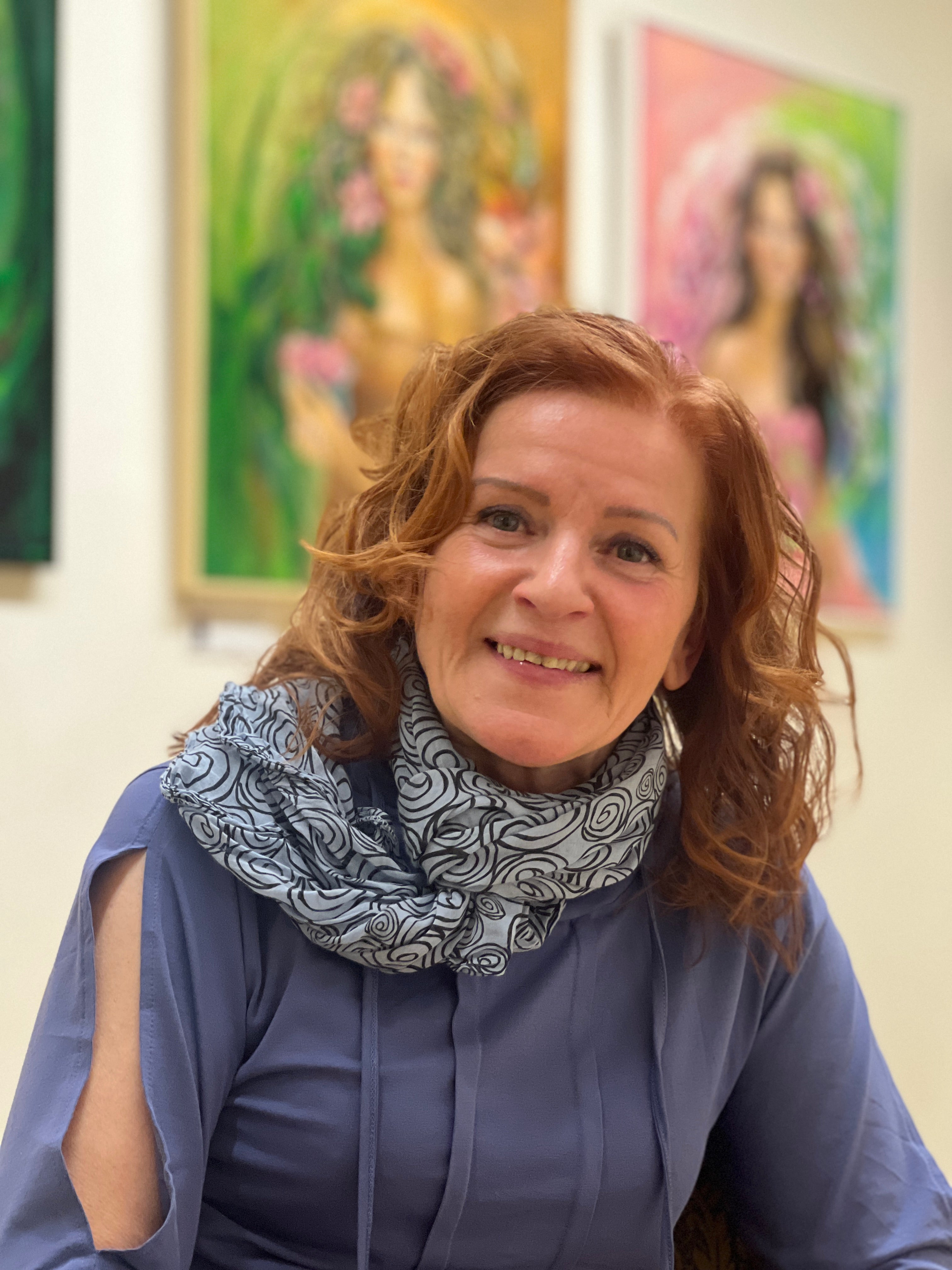 Fotka z Pražské galerie Lilie. Na portrétu je Romana Rosa, portrét malířky s obrazy v pozadí.